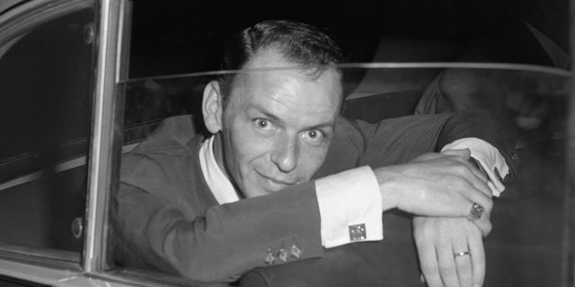 Hollywood singer, Frank Sinatra, is seen here looking quizzically into a press camera shortly after a conference with the Rome press where he denied reports that he had been booed and called off the stage of a Naples theater. The incident supposedly occurred when Sinatra's wife, actress Ava Gardner, billed to appear with him, failed to keep the engagement. According to press reports, the disappointed fans protested violently and walked out on the Sinatra performance. Nancy Olson Livingston said her husband, Alan W. Livingston, took a chance on the singer.