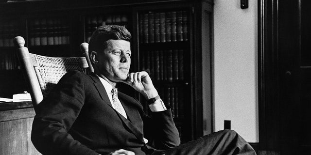 President John F. Kennedy (1917-1963), the 35th president of the United States, relaxes in his trademark rocking chair in the Oval Office.