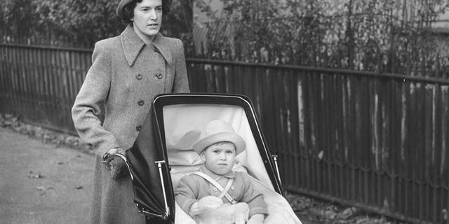 Prince Charles, heir to the British throne, riding in his pram pushed by his nanny, Mabel Anderson. 
