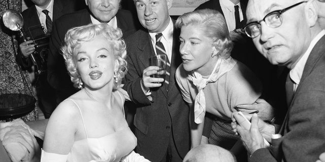 Actress Marilyn Monroe, left, is surrounded by photographers and journalists as she is interviewed by Phyllis Battelle, right. Nancy Olson Livingston described her first meeting with the blonde bombshell as "bizarre."