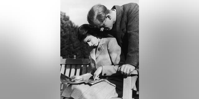 Princess Elizabeth, later Queen Elizabeth II, and her husband, Philip Mountbatten, study their wedding photographs while on honeymoon in Romsey, Hampshire, November 1947.