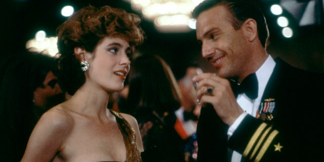 Kevin Costner wears black navy suit with Sean Young in movie No Way Out