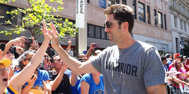 Golden State Warriors general manager Bob Myers high-fives fans during the championship parade in downtown Oakland, California, June 12, 2018.