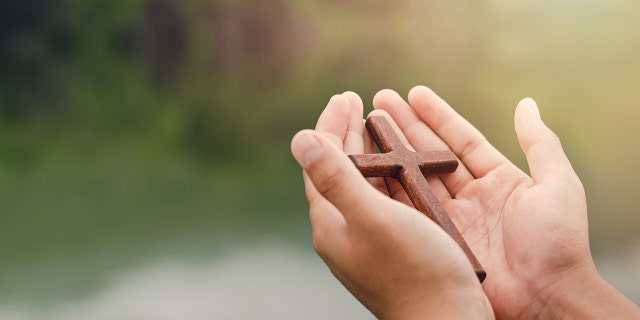 Hands holding wooden cross