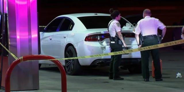 Police stand at a crime scene at a gas station on US Highway 301.