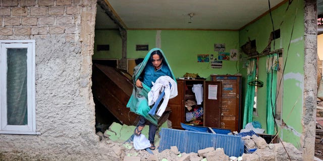 A man collects clothes from his house damaged following an earthquake in Cianjur, West Java, Indonesia on Tuesday Nov. 22, 2022.