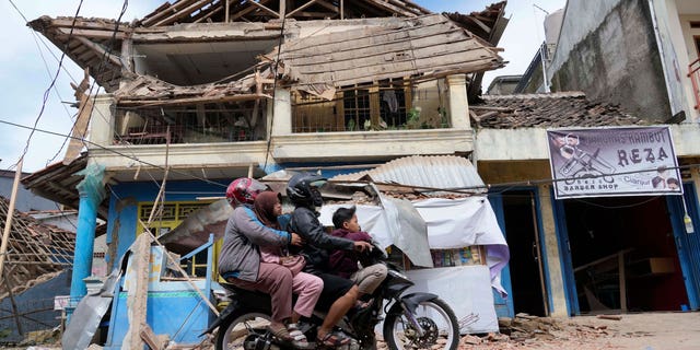 People ride a motorbike past a building damaged in Monday's earthquake in Cianjur, West Java, Indonesia, Tuesday, Nov. 22, 2022. 