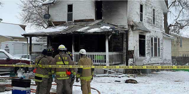Firefighters from Mason City, Iowa, stand outside the home that was damaged by a fire on Washington Avenue on Nov. 16, 2022. The fire was caused by an electrical power strip.