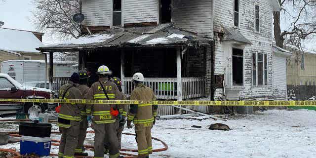 Firefighters from Mason City, Iowa, stand outside the home that was damaged by a fire on Washington Avenue on Nov. 16, 2022. The fire was caused by an electrical power strip.