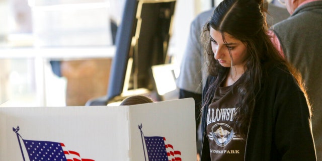 Zelly Muhammad, 15, watches her mother, Rebecca Muhammad, cast her ballot at Davenport North High School in Davenport, Iowa, on Election Day, Tuesday, Nov. 8, 2022. 