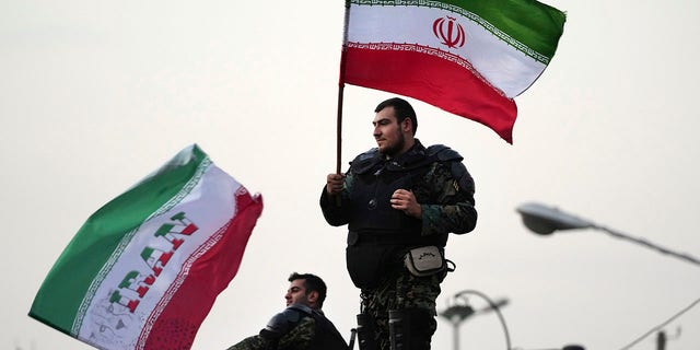 Two anti-riot police officers wave the Iranian flags during a street celebration after Iran defeated Wales in Qatar's World Cup, at Sadeghieh Sq. in Tehran, Iran, Friday, Nov. 25, 2022.  