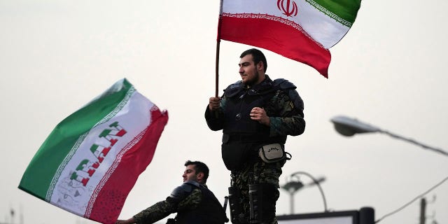 Two anti-riot police officers wave the Iranian flags during a street celebration after Iran defeated Wales in Qatar's World Cup at Sadeghieh Square in Tehran, Iran.