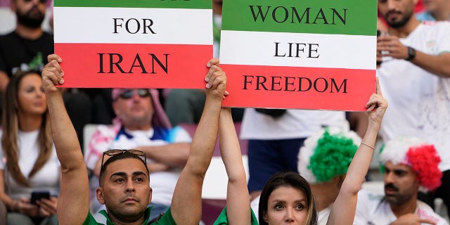 Fanii fotbalului iranien susțin pancarte pe care scrie Woman Life Freedom and Freedom For Iran, înaintea meciului de fotbal din Grupa B de la Cupa Mondială dintre Anglia și Iran pe Stadionul Internațional Khalifa din Doha, Qatar, luni, 21 noiembrie 2022.