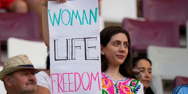 A woman holds up sign reading Woman Life Freedom, prior to the World Cup Group B soccer match between England and Iran at the Khalifa International Stadium in Doha, Qatar, Monday, Nov. 21, 2022.