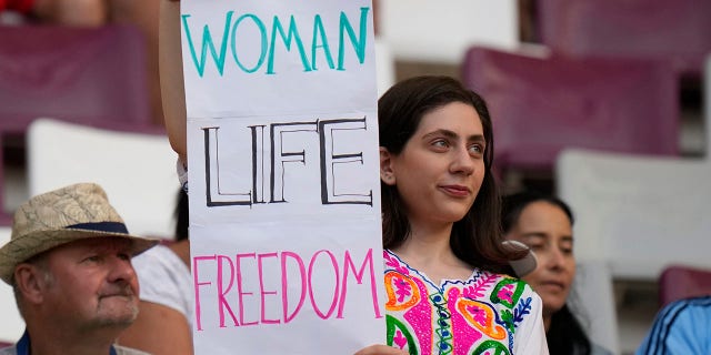 A woman holds up sign reading Woman Life Freedom, prior to the World Cup Group B soccer match between England and Iran at the Khalifa International Stadium in Doha, Qatar, Monday, Nov. 21, 2022.