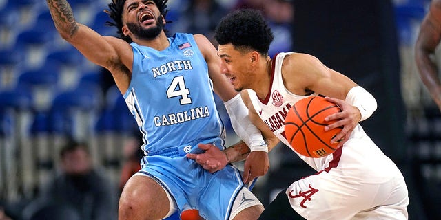 North Carolina guard R.J. Davis, #4, fouls Alabama guard Jahvon Quinerly during the first half of an NCAA college basketball game in the Phil Knight Invitational on Sunday, Nov. 27, 2022, in Portland, Oregon.