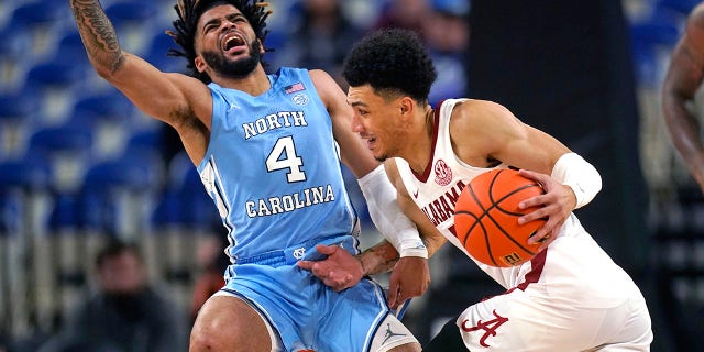 North Carolina guard RJ Davis, #4, fouls Alabama guard Jahvon Quinerly during the first half of an NCAA college basketball game at the Phil Knight Invitational on Sunday, November 27, 2022, in Portland, Oregon.