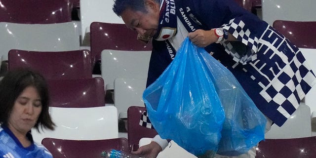 Japan supporters clean the stands at the end of the World Cup group E soccer match between Germany and Japan, at the Khalifa International Stadium in Doha, Qatar, Wednesday, Nov. 23, 2022.