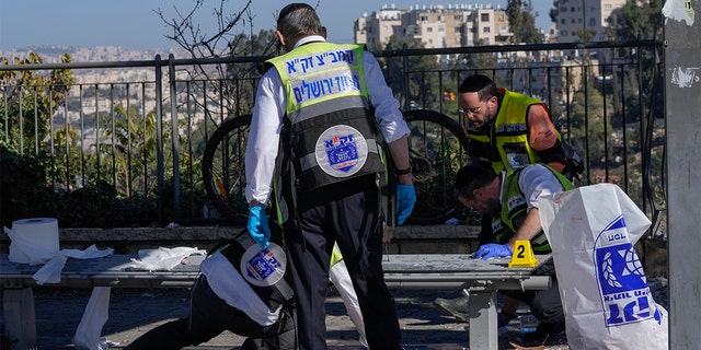 Members of the Zaka Rescue and Recovery team clean up blood from the scene of an explosion at a bus stop in Jerusalem, Wednesday, November 23, 2022. 