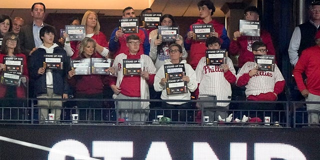 First lady Jill Biden, third from left in front, holds signs for Stand Up to Cancer during Game 4 of the World Series between the Houston Astros and Philadelphia Phillies, Nov.  2, 2022, in Philadelphia.