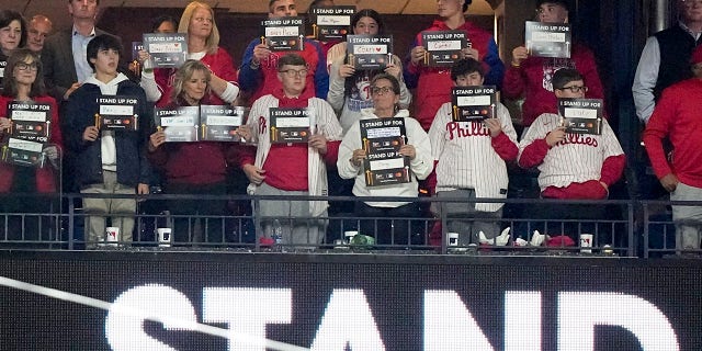 First lady Jill Biden, third from left in front, holds signs for Stand Up to Cancer during Game 4 of the World Series between the Houston Astros and Philadelphia Phillies, Nov. 2, 2022, in Philadelphia.