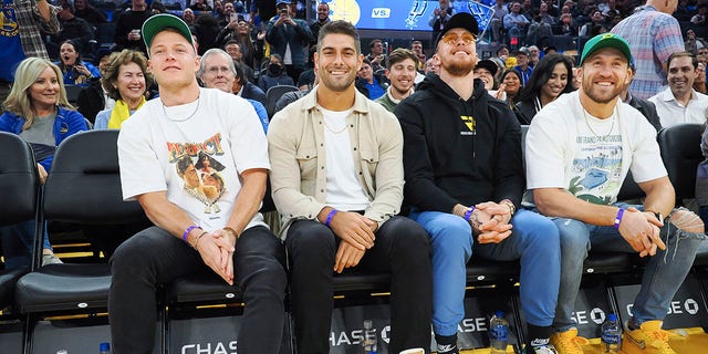 San Francisco 49ers players, left to right, running back Christian McCaffrey, quarterback Jimmy Garoppolo, tight end George Kittle and fullback Kyle Juszczyk sit courtside during the second quarter between the Golden State Warriors and San Antonio Spurs at Chase Center in San Francisco Nov. 14, 2022.