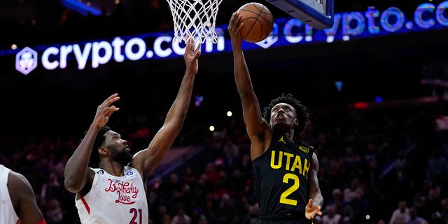 Utah Jazz's Collin Sexton, right, goes up for a shot against Philadelphia 76ers' Joel Embiid during the second half of an NBA basketball game, Sunday, Nov. 13, 2022, in Philadelphia.