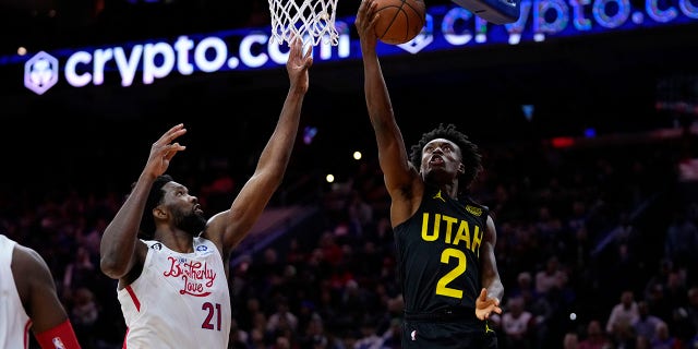 Utah Jazz's Collin Sexton, right, goes up for a shot against Philadelphia 76ers' Joel Embiid during the second half of an NBA basketball game, Sunday, Nov. 13, 2022, in Philadelphia.