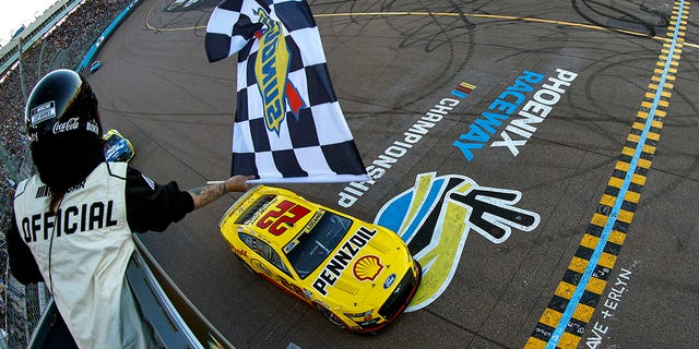Joey Logano, driver of the No. 22 Shell Pennzoil Ford, takes the checkered flag to win the NASCAR Cup Series Championship at Phoenix Raceway on Nov. 6, 2022, in Avondale, Arizona.