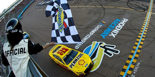 Joey Logano, driver of the No. 22 Shell Pennzoil Ford, takes the checkered flag to win the NASCAR Cup Series Championship at Phoenix Raceway on Nov. 6, 2022, in Avondale, Arizona.