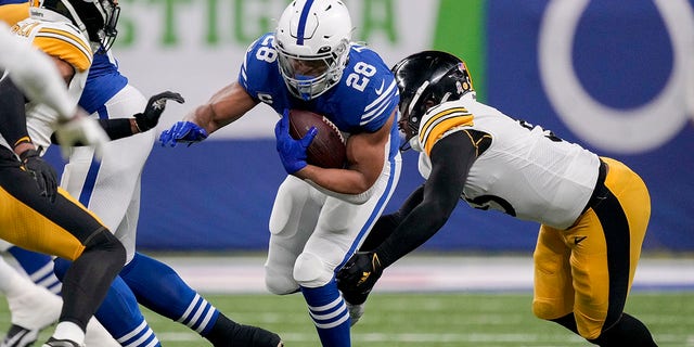 November 28, 2022;  Indianapolis, Indiana, United States;  Indianapolis Colts running back Jonathan Taylor (28) works to get past Pittsburgh Steelers inside linebacker Devin Bush (55) during the first half at Lucas Oil Stadium.