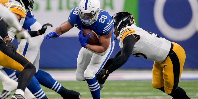 November 28, 2022;  Indianapolis, Indiana, United States;  Indianapolis Colts running back Jonathan Taylor (28) works to get past Pittsburgh Steelers inside linebacker Devin Bush (55) during the first half at Lucas Oil Stadium.