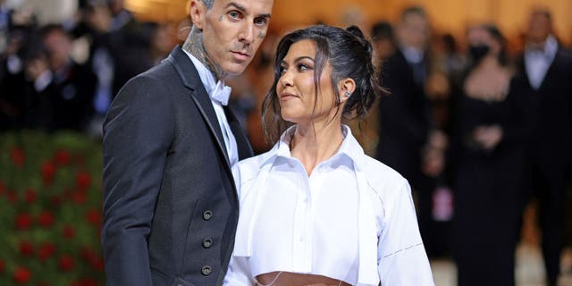 Travis Barker and Kourtney Kardashian pose at the 2022 Met Gala wearing Thom Browne.