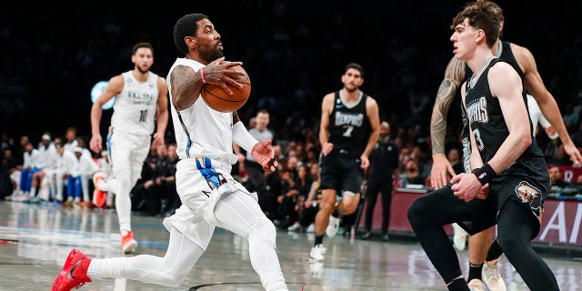 Brooklyn Nets guard Kyrie Irving dribbles against Memphis Grizzlies forward Jake LaRavia, Sunday, Nov. 20, 2022, in New York.