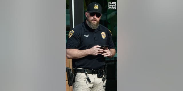 Moab Police Officer Eric Pratt is seen on his phone in Moab, Utah, Saturday, October 29, 2022.