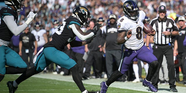 Baltimore Ravens quarterback Lamar Jackson (8) scrambles for yardage against Jacksonville Jaguars linebacker Devin Lloyd (33) during the first half of an NFL football game, Sunday, Nov. 27, 2022, in Jacksonville, Fla.