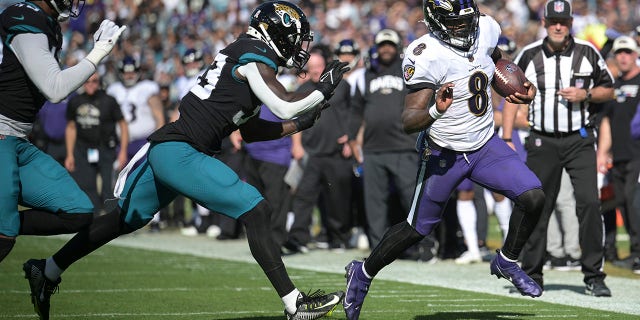 Baltimore Ravens quarterback Lamar Jackson (8) scrambles for yardage against Jacksonville Jaguars linebacker Devin Lloyd (33) during the first half of an NFL football game, Sunday, Nov. 27, 2022, in Jacksonville, Fla.