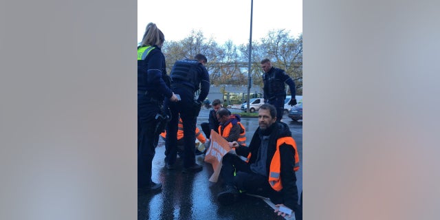 Climate change activists glue themselves to the road during a protest in Cologne, Germany, Nov. 24, 2022. 