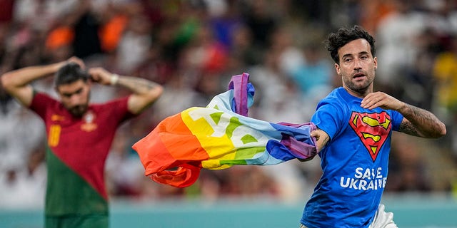 Un invasor de la cancha cruza la cancha con una bandera del arcoíris durante el partido de fútbol del Grupo H de la Copa Mundial entre Portugal y Uruguay en el Estadio Lusail en Lusail, Qatar, el lunes 28 de noviembre de 2022. 