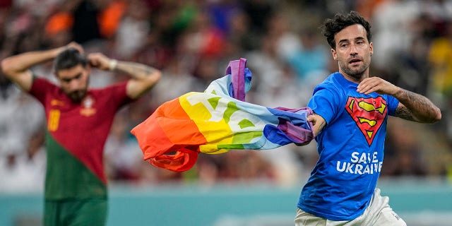 A pitch invader runs across the field with a rainbow flag during the World Cup Group H soccer match between Portugal and Uruguay, at the Lusail Stadium in Lusail, Qatar, Monday, Nov. 28, 2022. 