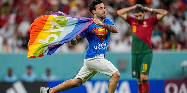 A pitch attacker runs across the field with a rainbow flag during the World Cup Group H soccer match between Portugal and Uruguay at Lusail Stadium in Lusail, Qatar, Monday, Nov. 28, 2022.