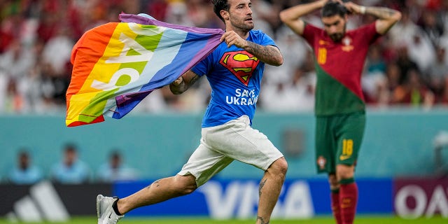 A pitch invader runs across the pitch with a rainbow flag during the World Cup group H soccer match between Portugal and Uruguay, at Lusail Stadium in Lusail, Qatar on Monday, Nov. 28, 2022.