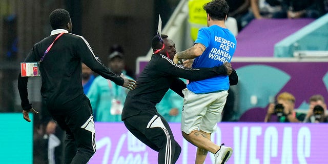 A pitch invader runs is caught while running across the field with a rainbow flag during the World Cup Group H soccer match between Portugal and Uruguay, at the Lusail Stadium in Lusail, Qatar, Monday, Nov. 28, 2022.