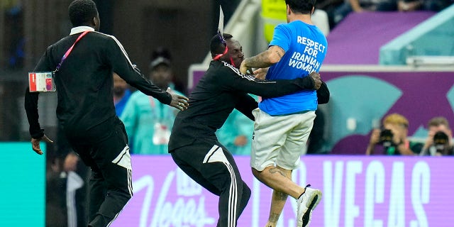 A pitch invader is caught crossing the pitch with a rainbow flag during the World Cup group H soccer match between Portugal and Uruguay, at Lusail Stadium in Lusail, Qatar on Monday, Nov. 28, 2022.