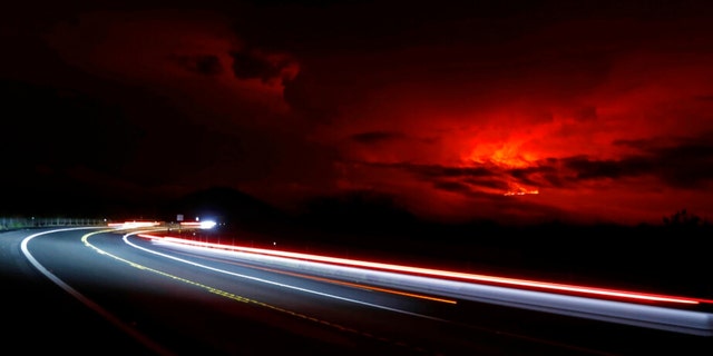 In this long camera exposure, cars drive down Saddle Road as Mauna Loa erupts in the distance, Monday, Nov. 28, 2022, near Hilo, Hawaii. 