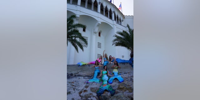 Elle Jimenez, a full-time professional mermaid and mermaid swim instructor, hosted a PADI-certified advanced mermaid course at Casino Point on Catalina Island, California. Here, she poses with her hand raised alongside her students on Sunday, Oct. 23. The group wears mermaid tails with smiles.
