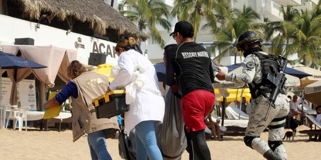 Forensic technicians and security forces move one of three bodies that washed ashore at Icacos Beach in Acapulco, Mexico, Nov. 12, 2022.