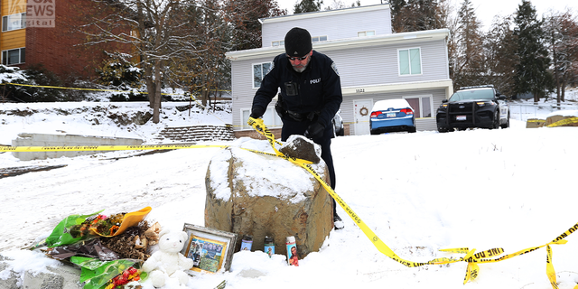A Moscow police officer is seen fixing the crime scene tape outside the home where four University of Idaho students were stabbed to death.