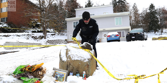 A Moscow police officer is seen fixing the crime scene tape outside of the home where four University of Idaho students were stabbed to death.