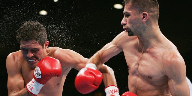 Nedal Hussein, a la derecha, se conecta con un derecho a la cara de Oscar Larios durante una pelea por el campeonato mundial de peso supergallo WBC en el MGM Grand Garden Arena el 27 de noviembre de 2004 en las Vegas.  Larios derrotó a Hussein por decisión unánime. 